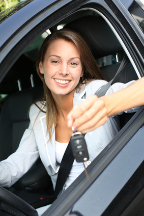 Cheerful girl holding car keys from window